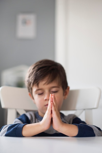 Retrato de menino rezando em casa