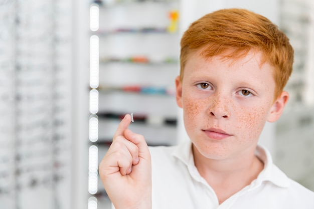 Retrato de menino sardento com lente de contato na clínica de óptica