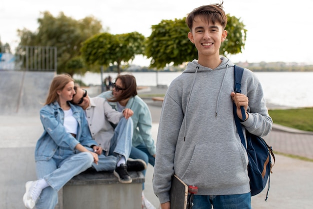 Retrato de menino segurando um skate ao lado dos amigos