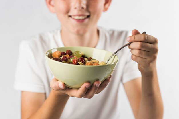 Retrato, de, menino sorridente, segurando tigela, de, salada fruta, contra, fundo branco