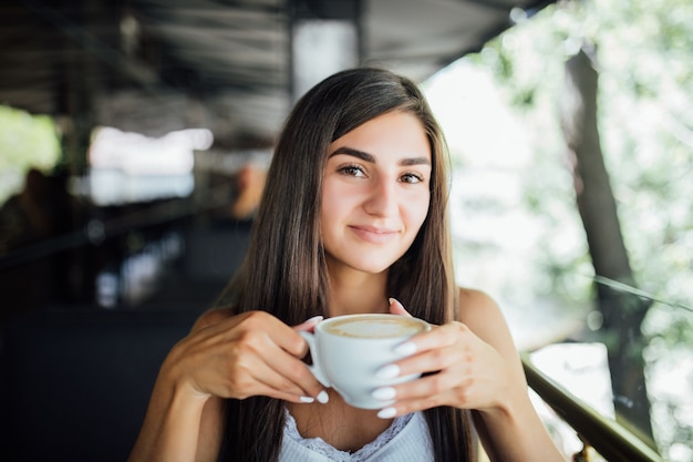 Retrato de moda ao ar livre de linda jovem bebendo chá e café