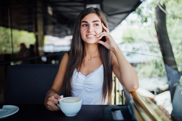 Retrato de moda ao ar livre de linda jovem bebendo chá e café