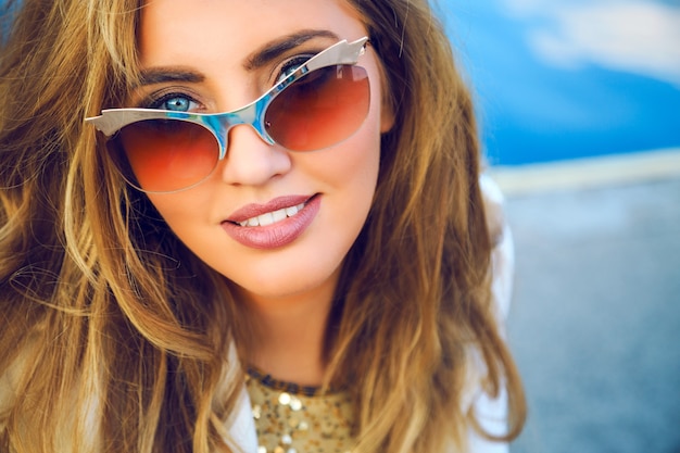 Retrato de moda ao ar livre de mulher bonita com uma pele perfeita, sonhando sozinha e olhando no chão. e curtir seus pensamentos, ter maquiagem natural, posando no porto marítimo.