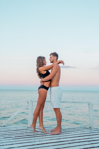 Retrato de moda ao ar livre de um casal muito sexy apaixonado por abraços na incrível praia tropical usando roupas de banho estilosas