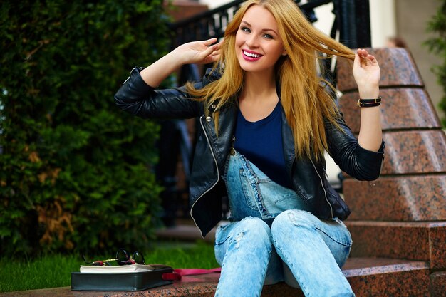 retrato de modelo engraçado engraçado moderno sexy urbano menina mulher jovem e bonita elegante pano moderno brilhante ao ar livre, sentado no parque em jeans em um banco
