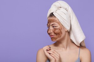 Foto grátis retrato de modelo feminino aplica máscara de chocolate no rosto, tem expressão positiva, olha de lado