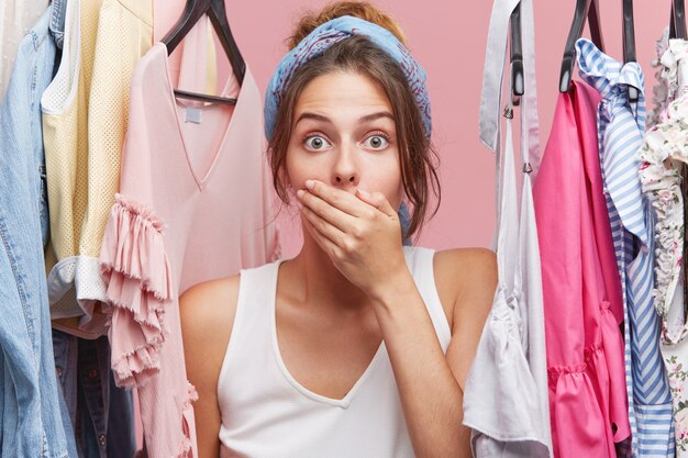 Retrato de modelo feminino chocado, cobrindo a boca com a mão, olhando com os olhos esbugalhados, esquecendo-se de passar a roupa, vestida para reunião de negócios. Pessoas, choque, grande surpresa