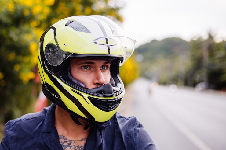 Foto grátis retrato de motociclista com capacete amarelo em motocicleta na beira de uma estrada movimentada na tailândia