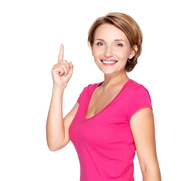 Retrato de mulher adulta feliz apontando para cima com o dedo sobre a parede branca