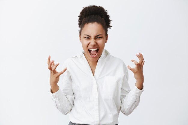 Retrato de mulher afro-americana angustiada, irritada, indignada, sentindo-se intensa, gritando e carrancuda querendo matar