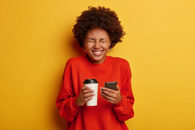 Retrato de mulher afro-americana radiante fazendo anotações em smartphone