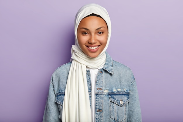 Retrato de mulher alegre e bonita com visões islâmicas, sorrindo gentilmente para a câmera