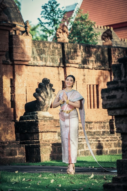 Retrato de mulher asiática encantadora usando um lindo vestido tailandês típico da cultura de identidade da Tailândia em um templo antigo ou lugar famoso com pose graciosa