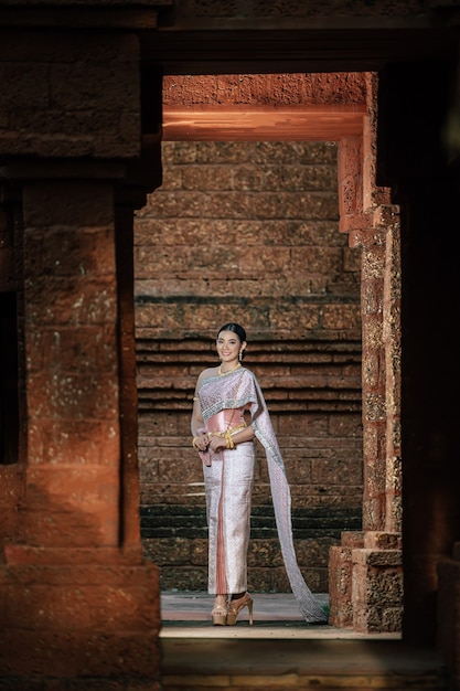 Foto grátis retrato de mulher asiática encantadora usando um lindo vestido tailandês típico da cultura de identidade da tailândia em um templo antigo ou lugar famoso com pose graciosa