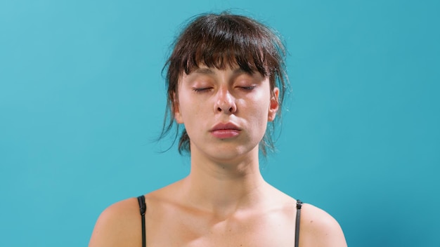 Retrato de mulher atlética respirando e relaxando após o treino, sentado com os olhos fechados na frente da câmera. Pessoa ativa respirando fundo para se recuperar da prática de ginástica.