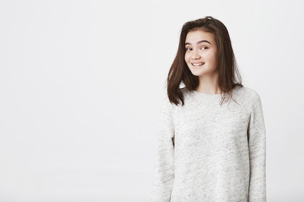 Retrato de mulher atraente na moda com sobrancelhas levantadas, sorrindo ansiosamente