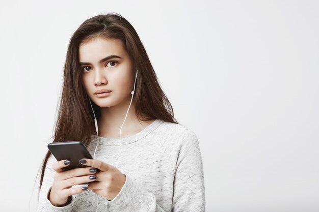 Retrato de mulher bonita e atraente caucasiano ouvindo música e mensagens com expressão casual.