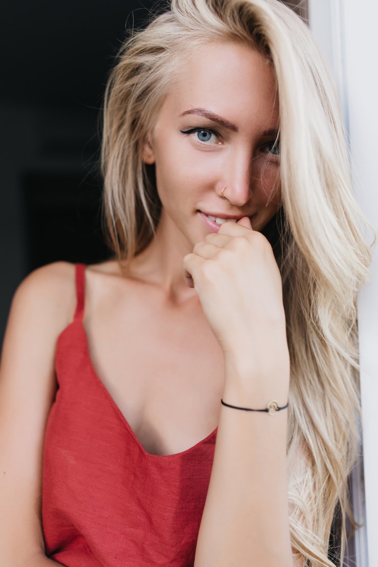 Foto grátis retrato de mulher bonita inspirada com olhos azuis. mulher loira de cabelos compridos em um pijama vermelho, expressando interesse.