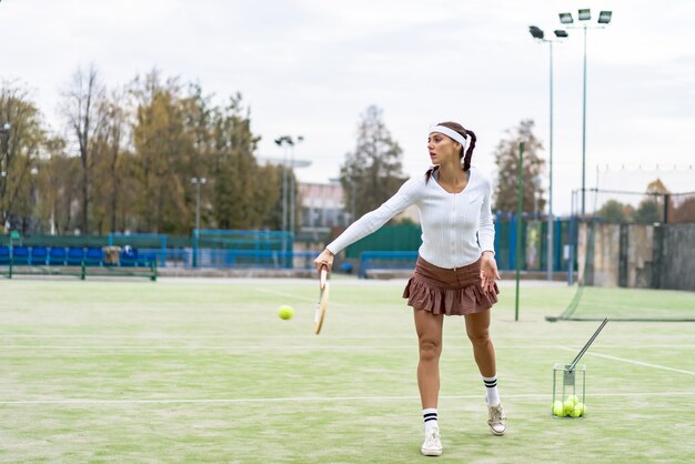 Retrato, de, mulher bonita, jogando tênis, ao ar livre