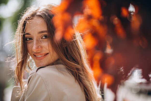 Retrato de mulher bonita no parque pelas folhas vermelhas