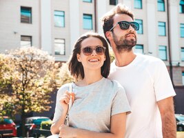 Retrato de mulher bonita sorridente e seu namorado bonito mulher em roupas casuais de verão família alegre feliz mulher se divertindo casal posando no fundo da rua em óculos de sol