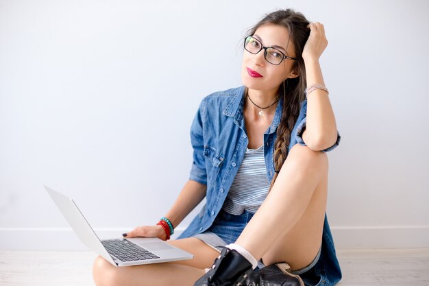 Retrato de mulher casual deslumbrante com laptop nas pernas