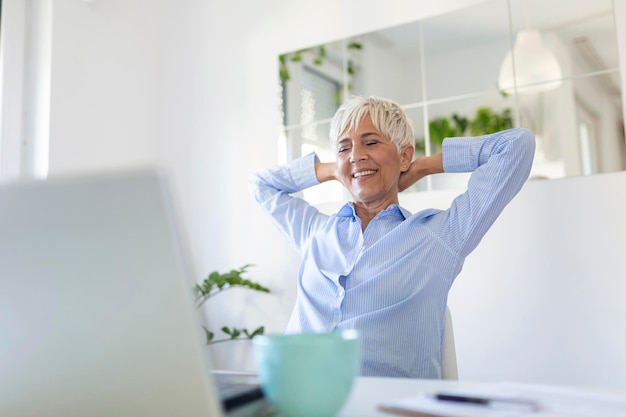 Retrato de mulher casual usando seu laptop enquanto está sentado no escritório em casa e trabalhando Uma atraente empresária de meia idade sentada na frente do laptop e gerenciando sua pequena empresa em casa