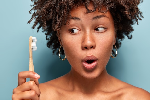 Retrato de mulher com corte de cabelo afro segurando uma escova de dentes