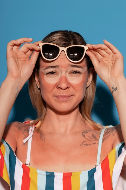 Retrato de mulher com marcas de queimaduras solares na pele e óculos de sol