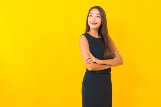 Retrato de mulher de negócios asiática jovem bonita sorrindo com ação sobre fundo de cor amarela.