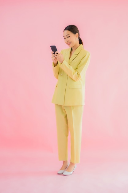 Retrato de mulher de negócios jovem asiática usando telefone celular inteligente com xícara de café na cor