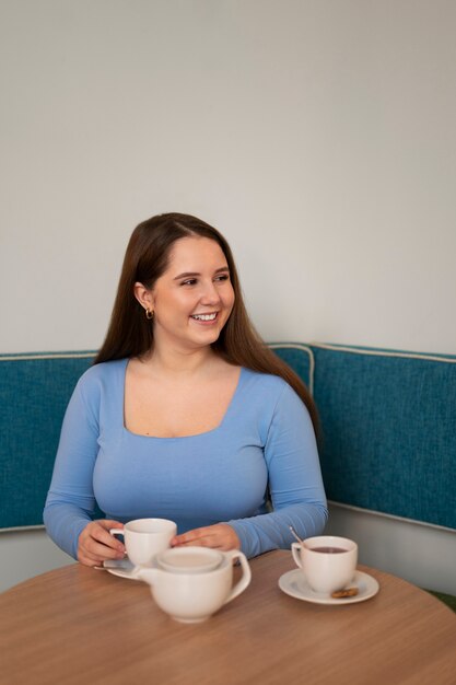 Retrato de mulher de tamanho grande desfrutando de uma bebida em um restaurante