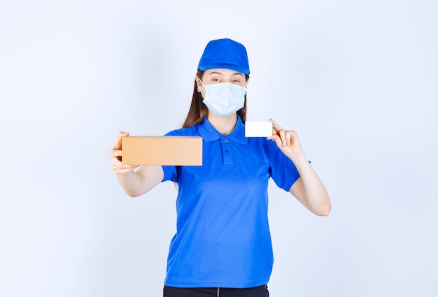 Retrato de mulher de uniforme e máscara médica segurando uma caixa de papel