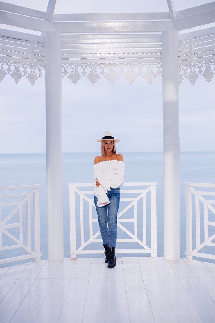 Foto grátis retrato de mulher elegante com um top branco volumoso e um chapéu clássico de luxo sob o arco esculpido