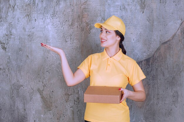 Foto grátis retrato de mulher entregadora com caixa de papelão mostrando a palma da mão aberta