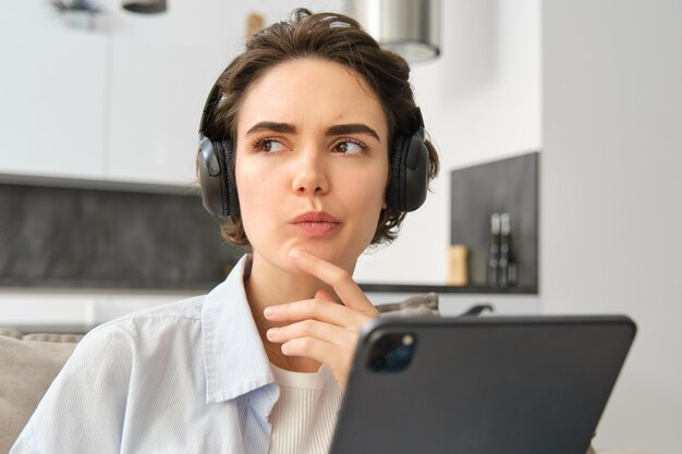 Retrato de mulher estudando ouvindo música em fones de ouvido pensando enquanto trabalhava em tablet digital wo