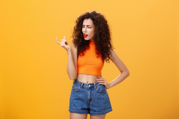 Retrato de mulher europeia mal-humorada, arrogante e descontente com penteado encaracolado e top cortado ...