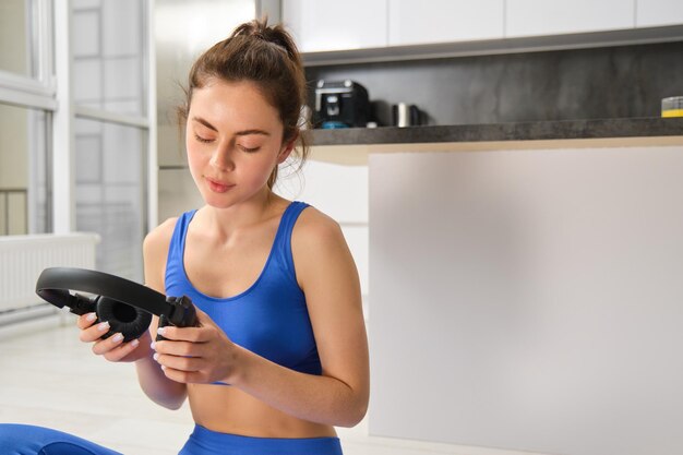 Foto grátis retrato de mulher fazendo exercícios de fitness em casa em tapete de ioga ouvindo música em fones de ouvido sem fio