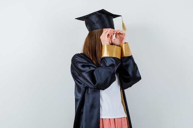 Retrato de mulher graduada mostrando gesto de óculos em roupas casuais, uniforme e olhando a vista frontal focada