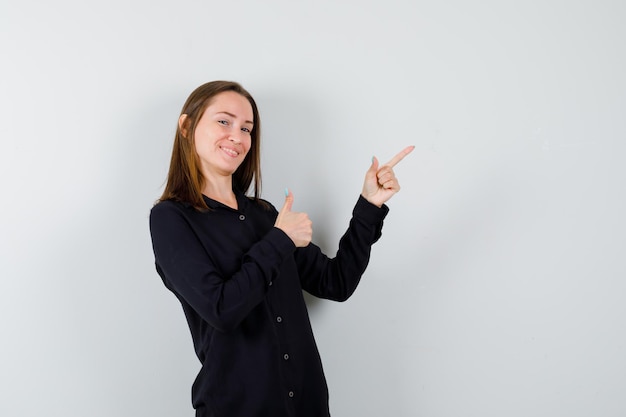 Retrato de mulher jovem apontando para o canto superior direito