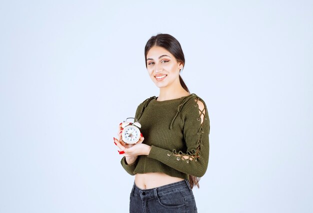 Retrato de mulher jovem, apresentando despertador.