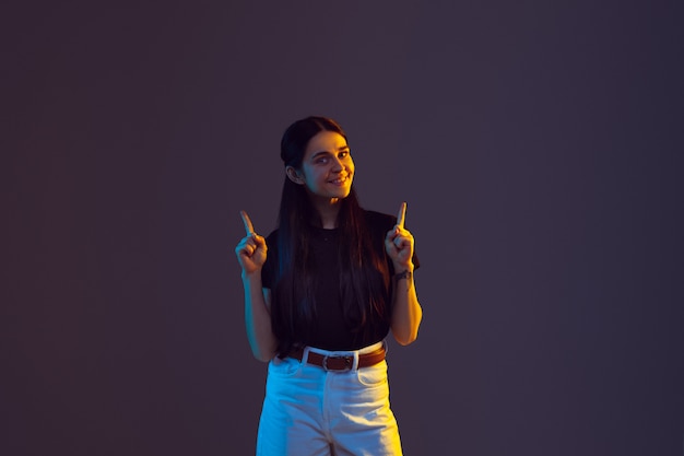 Retrato de mulher jovem caucasiano isolado no fundo do estúdio na luz de neon. bela modelo feminino.