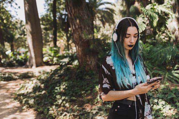 Retrato, de, mulher jovem, com, headphone, ligado, dela, cabeça, percorrendo, telefone pilha