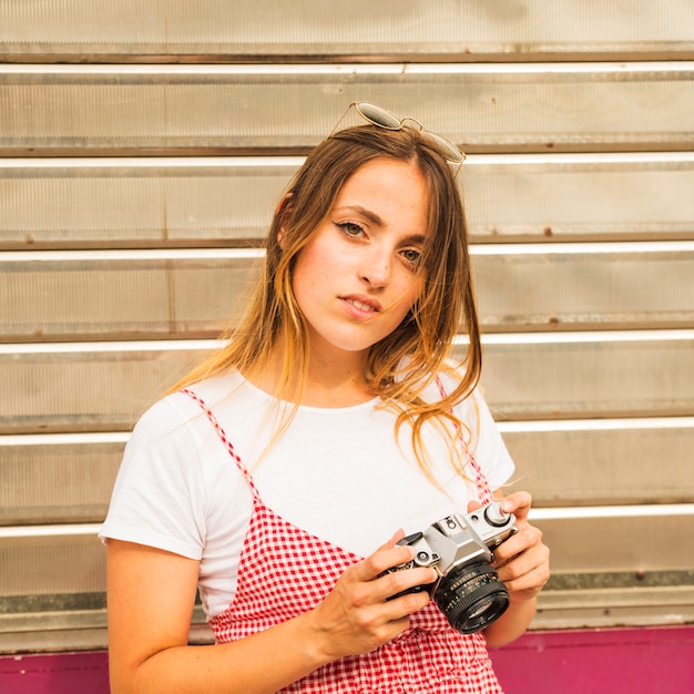 Foto grátis retrato, de, mulher jovem, com, óculos de sol, sobre, dela, cabeça, segurando, câmera