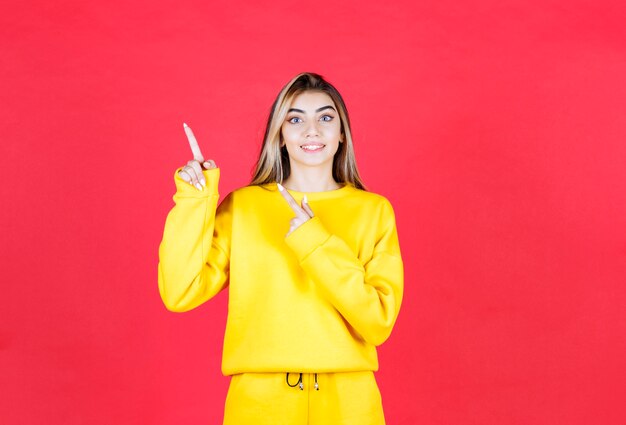 Retrato de mulher jovem com roupa amarela apontando para algum lugar