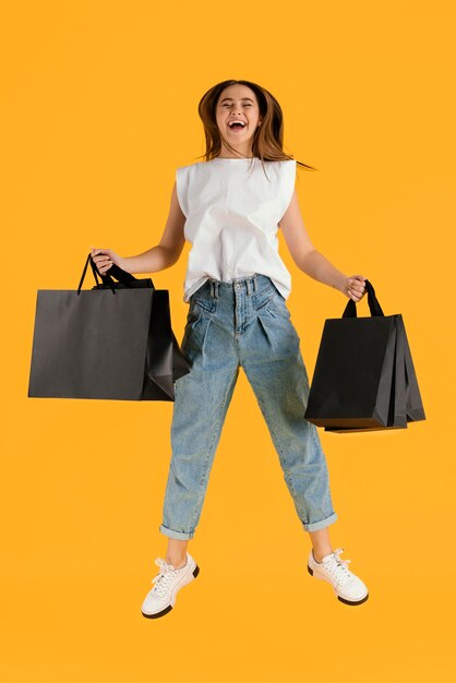 Retrato de mulher jovem com sacolas de compras pulando