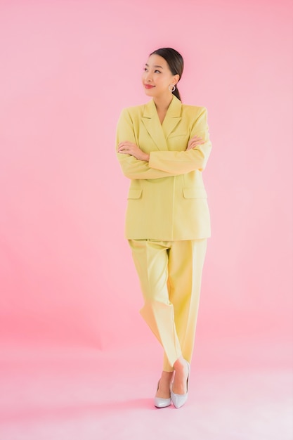Retrato de mulher jovem e bonita asiática sorrindo em ação na cor rosa