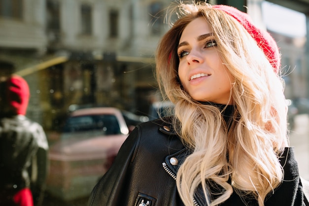 Retrato de mulher jovem e bonita com cabelo longo ondulado e grandes olhos verdes sorri, seu sorriso encantador e caminha para o almoço. Mulher bonita andando na rua ensolarada