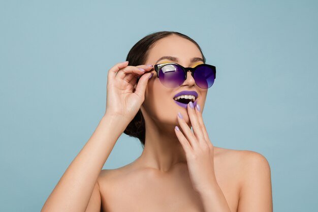 Retrato de mulher jovem e bonita com maquiagem brilhante isolada na parede azul