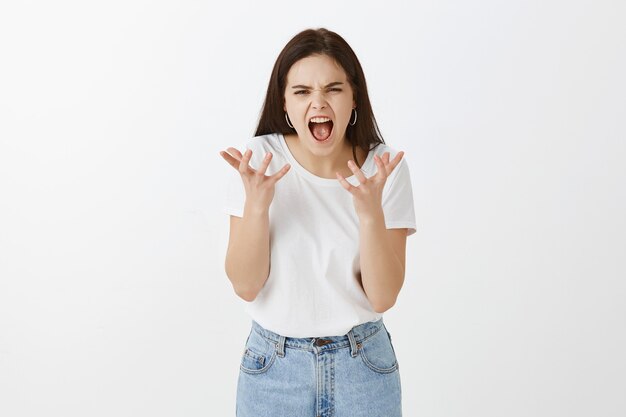 Retrato de mulher jovem estressada posando contra uma parede branca